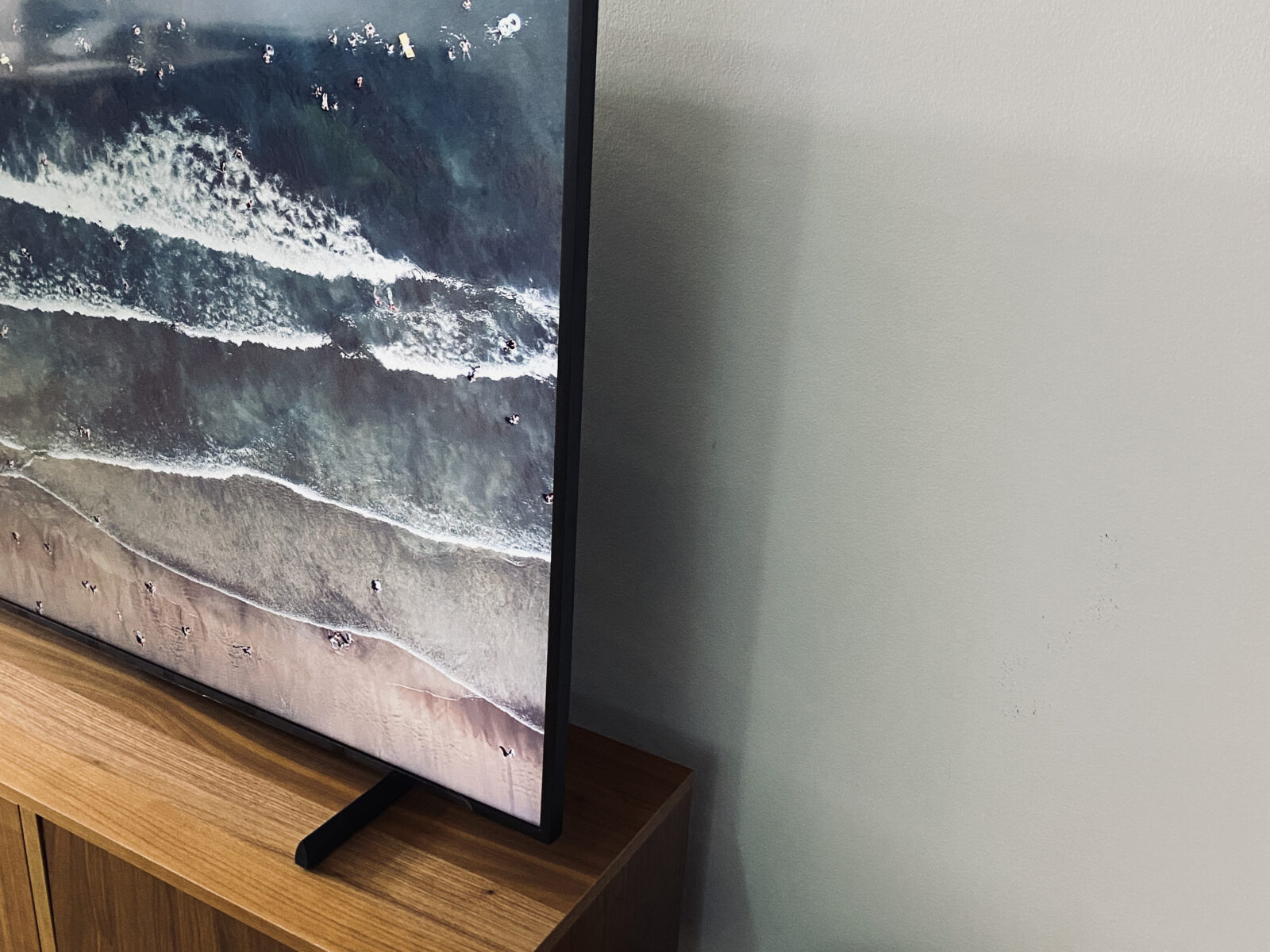 Side view of the 65-inch Samsung Frame TV 2021 model on a brown wood entertainment unit